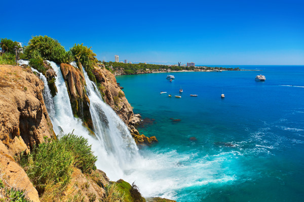 a stunning waterfall cascading into turquoise waters surrounded by green foliage and a clear blue sky ideal for nature lovers and relaxation