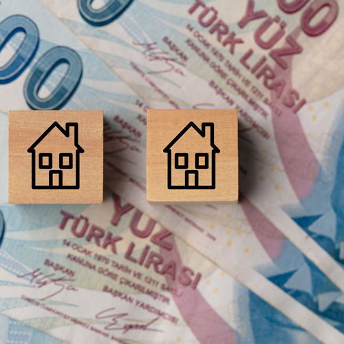 wooden blocks with house icons on Turkish lira banknotes depicting real estate investment and housing market trends 2 keys to success