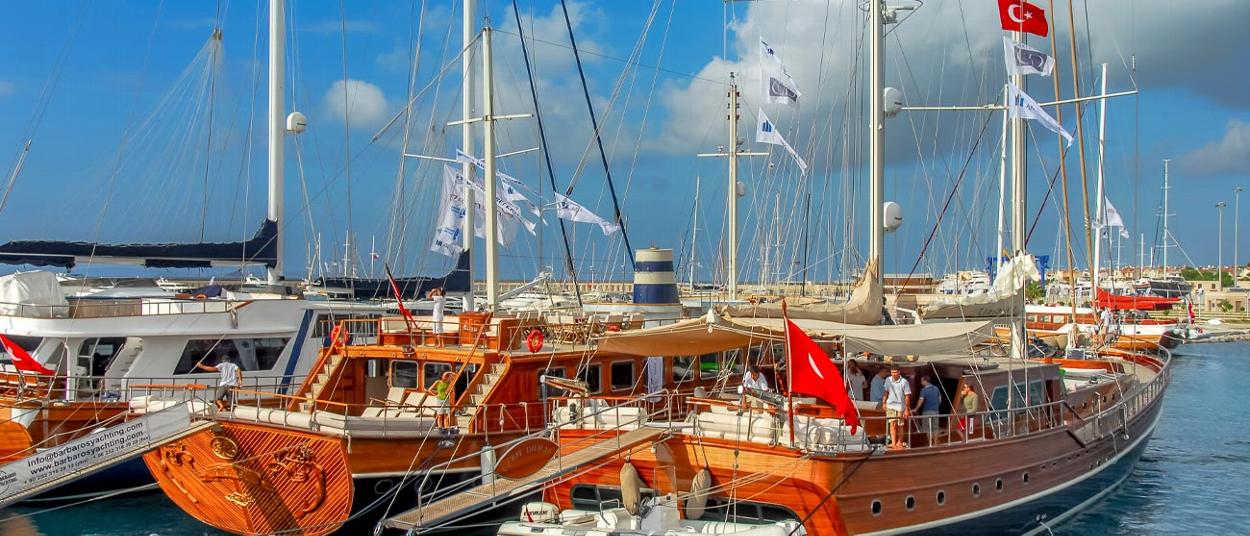 boats docked in a marina with Turkish flags sailing under a clear blue sky showcasing wooden yachts three elegant vessels